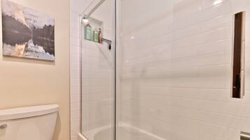 Een badkamer met toilet, een douche in een glazen cabine en een bad.