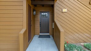 A wooden exterior hallway leading to a door with a number plate '21'.
