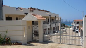 A gated entrance to a building with a tiled roof, a metal gate, and a clear view of the sea in the background. - Townhouse with stunning view, only 5 minutes walk to the beach (Vibo Valentia)