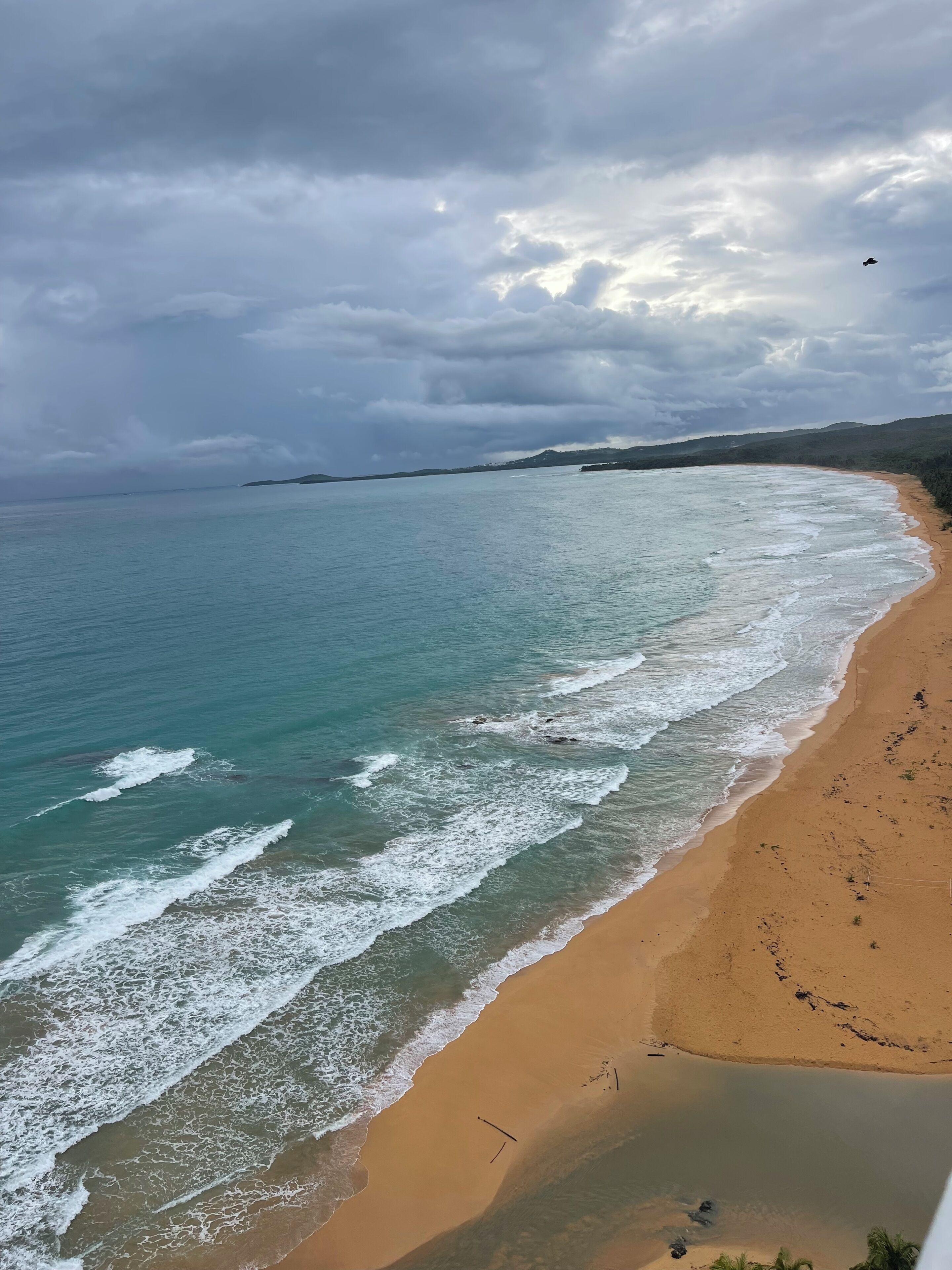 Une plage avec des vagues, un rivage sablonneux et un ciel nuageux.