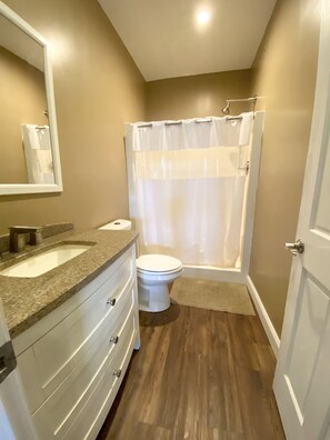 Une salle de bain avec un meuble-lavabo à deux vasques, des toilettes et une douche avec un rideau.