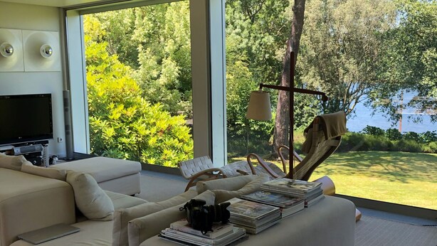 A modern living room with a large window, a sofa, a TV, and a lamp.