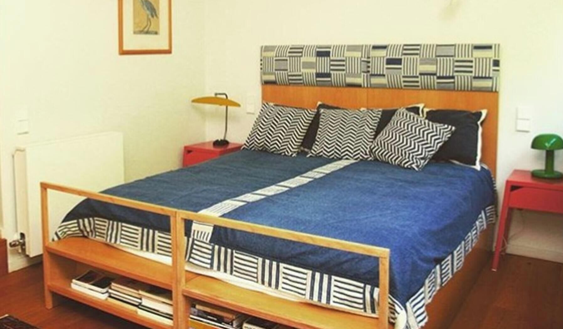 Ein Doppelbett mit gemustertem Kopfteil, ein Nachttisch mit Lampe und ein Bücherregal.