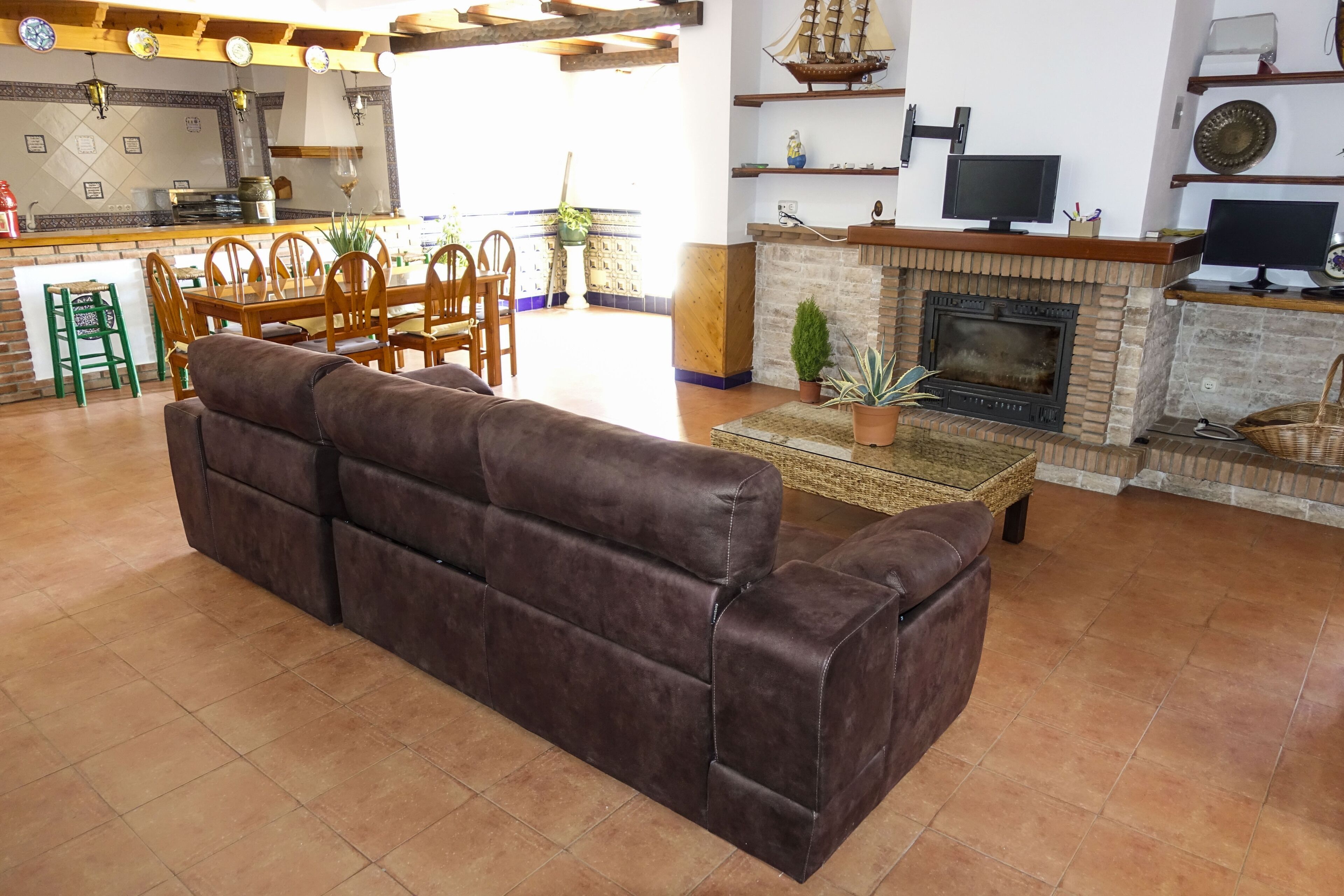 A living room with a brown leather sofa, a fireplace, and a television.