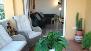 A cozy living area with wicker furniture, a potted plant, and a tiled floor.