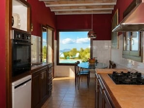 A kitchen with a view of a swimming pool, a dining area, and a built-in oven.