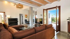 Ein Wohnzimmer mit einem braunen Sofa, einem Fernseher, einem Klavier und einem Kamin.