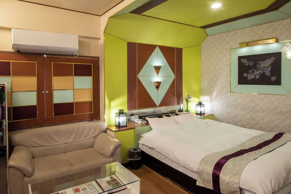 Une chambre d’hôtel équipée d’un lit, d’un canapé, d’une table en verre et d’un climatiseur fixé au mur.