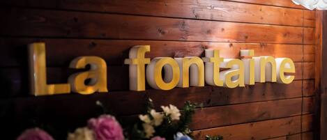 A wooden wall with the words "La fontaine" in gold letters.