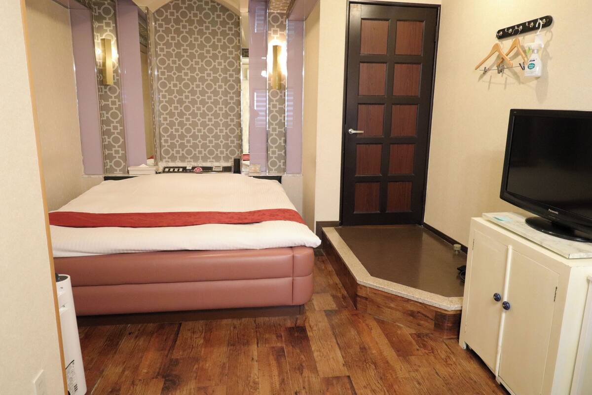 Une chambre d’hôtel équipée d’un lit, d’une télévision, d’une armoire et d’un espace douche.