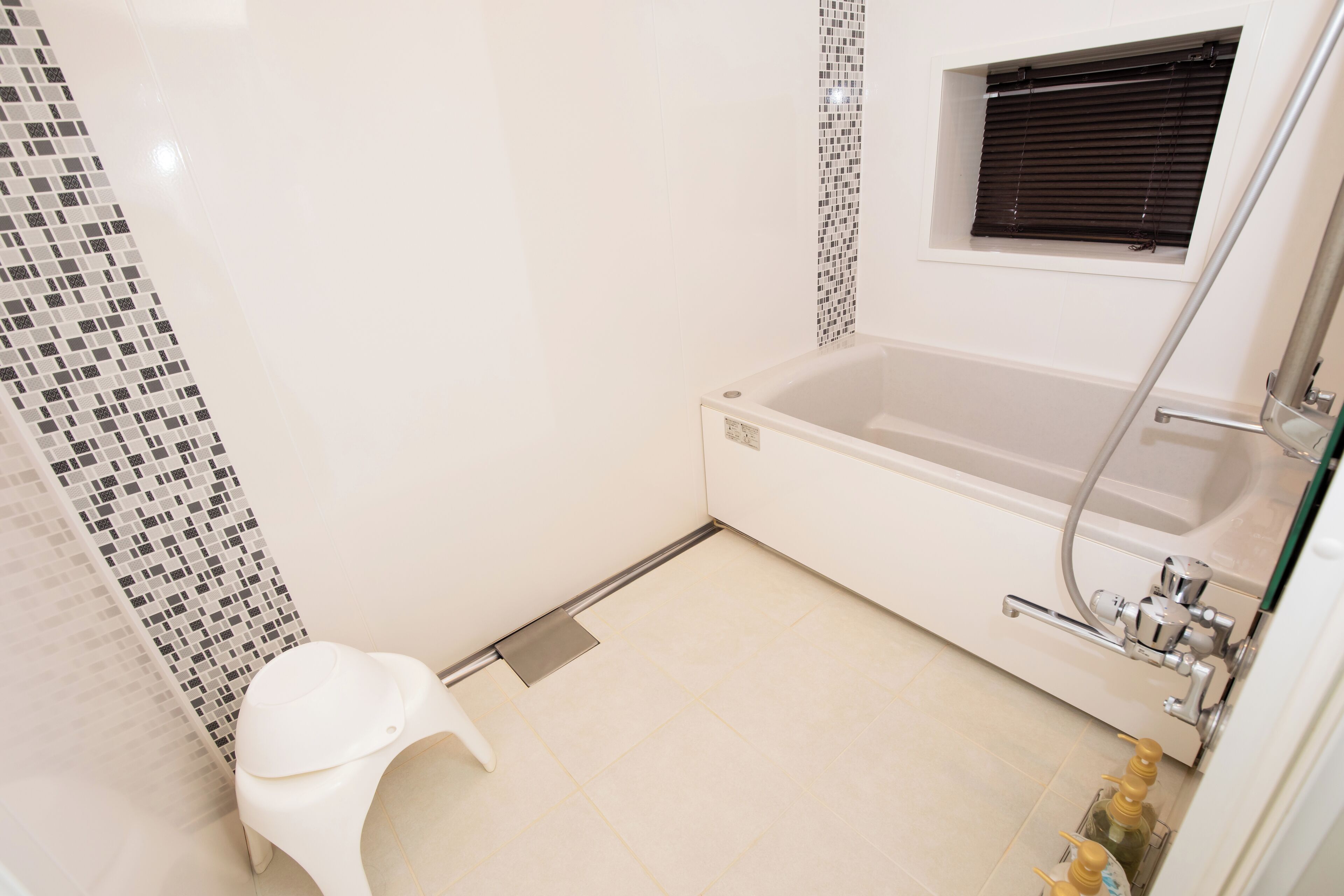 Ein Badezimmer mit Badewanne, Toilette und einem Fenster mit Jalousien.