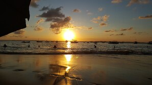 Une scène de plage avec des bateaux et des personnes au coucher du soleil.