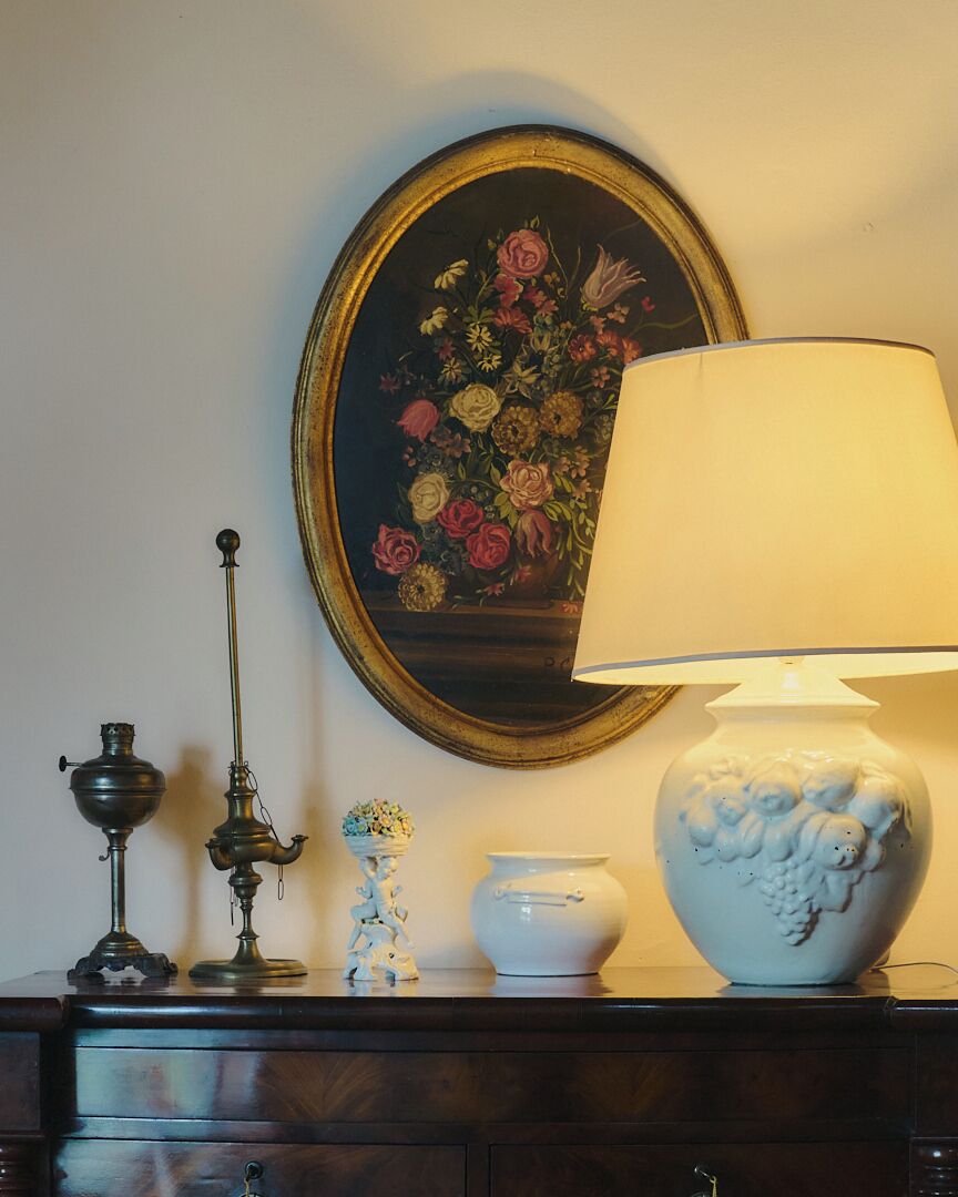 En mørk trækommode med en lampe, en vase og en lille figur.