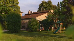 Ein Haus mit geneigtem Dach, einer Ziegel-Fassade und einer grünen Rutsche im Garten.