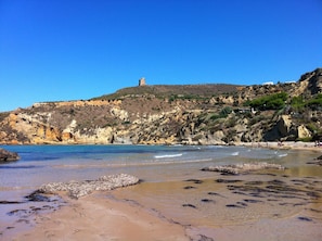 A coastal landscape with a prominent hill and a lighthouse.