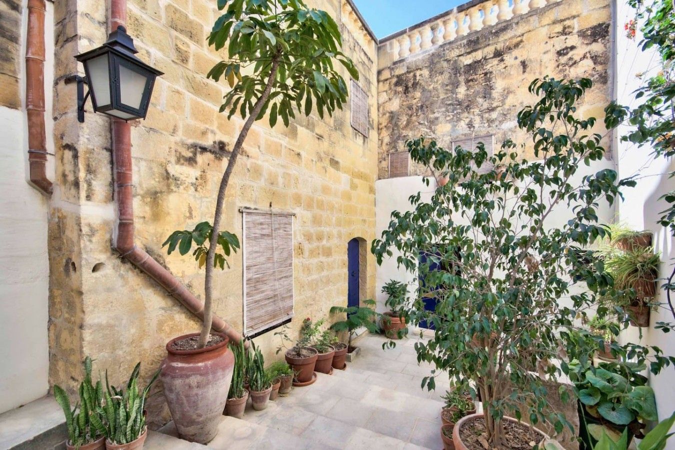 A courtyard with stone walls, potted plants, and a traditional lantern.