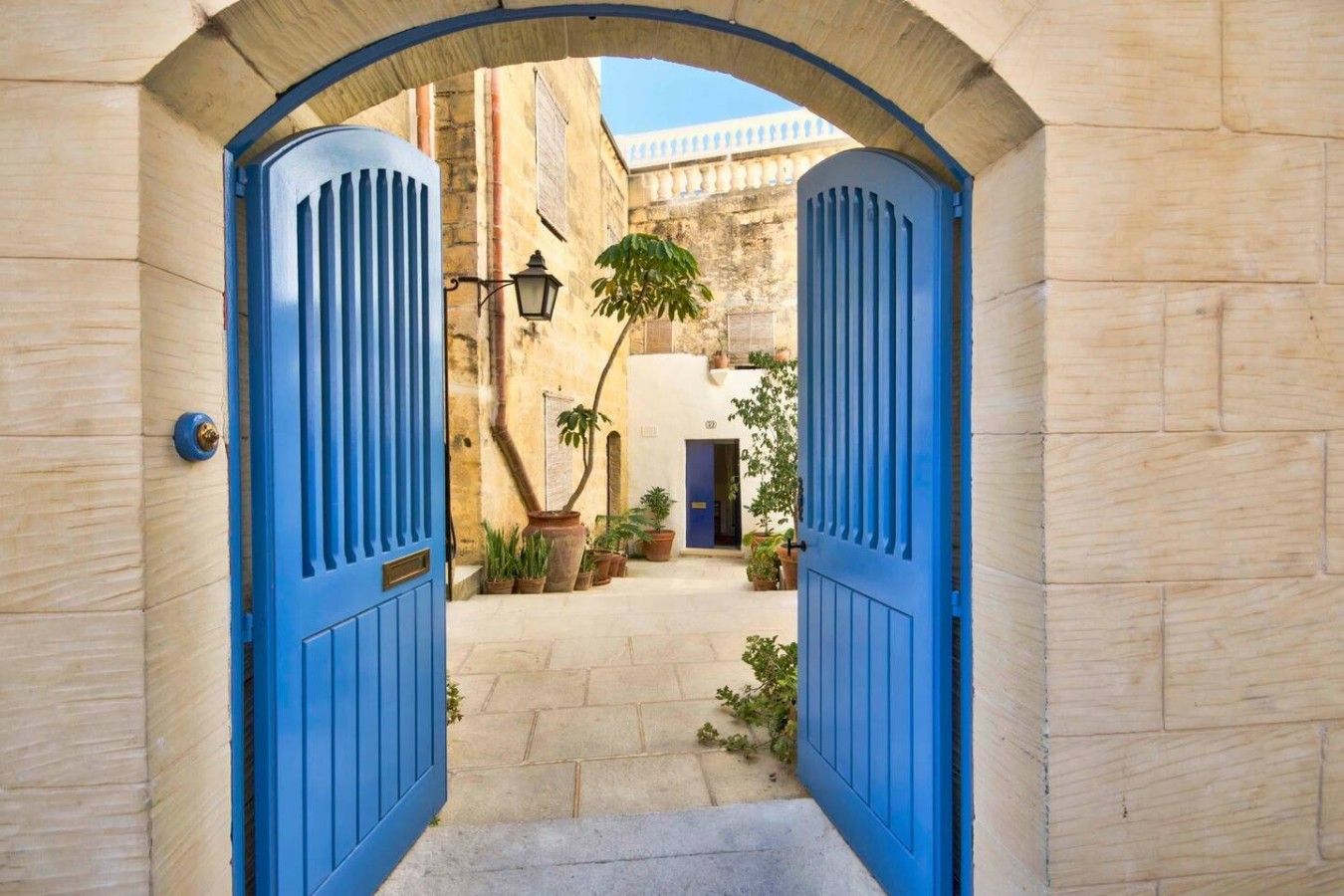 A narrow alleyway with a blue archway leading to a courtyard.