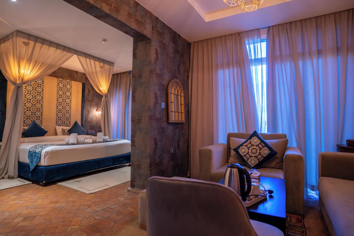 A hotel room with a bed, a sofa, a coffee table, and a window with curtains.