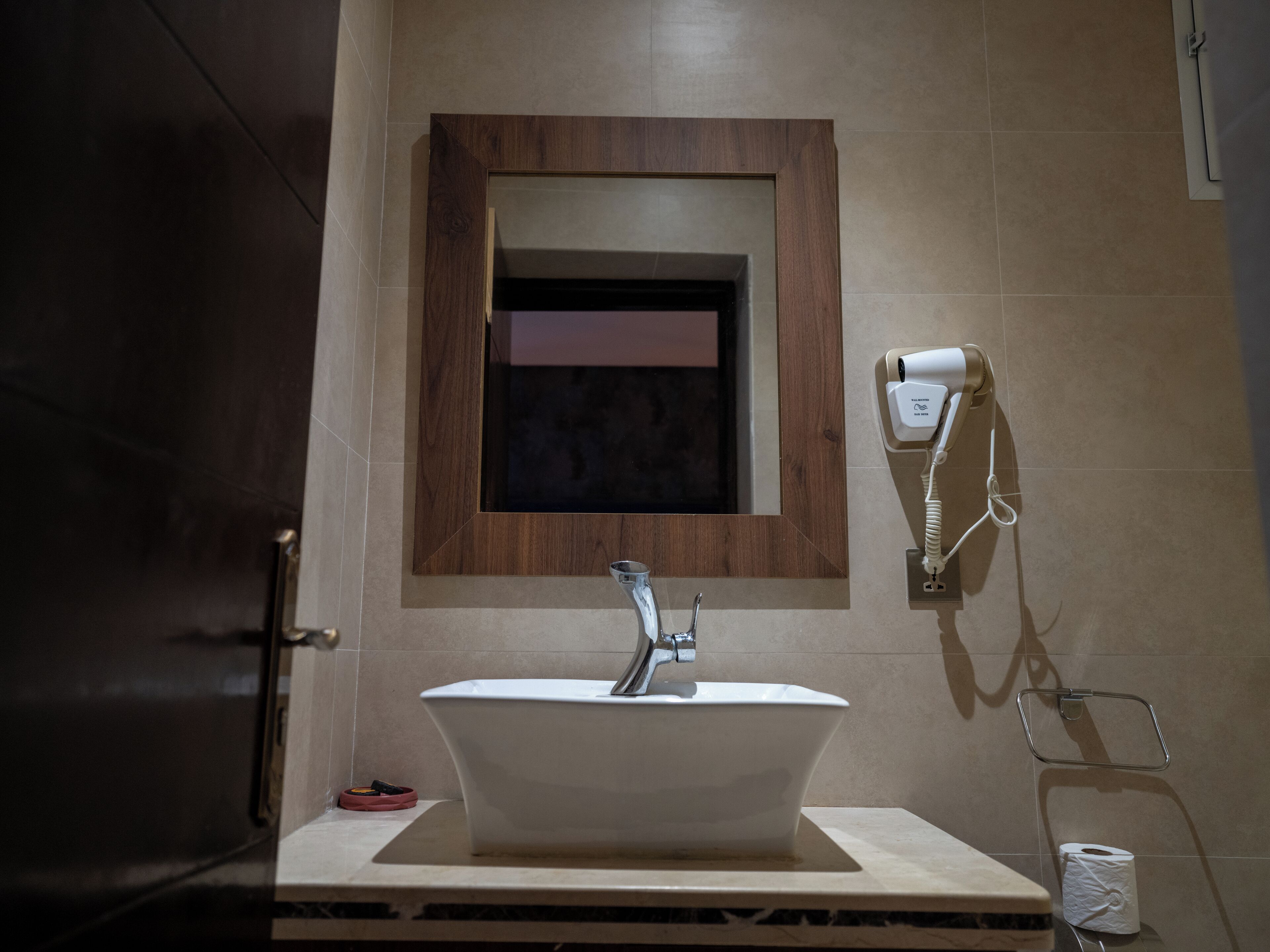 Ein Badezimmer mit freistehender Badewanne, einem Handtuchhalter und einem an der Wand befestigten Föhn.