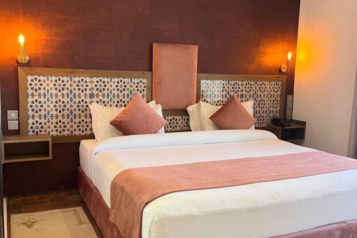 A hotel room with a bed, nightstands, and a decorative headboard.