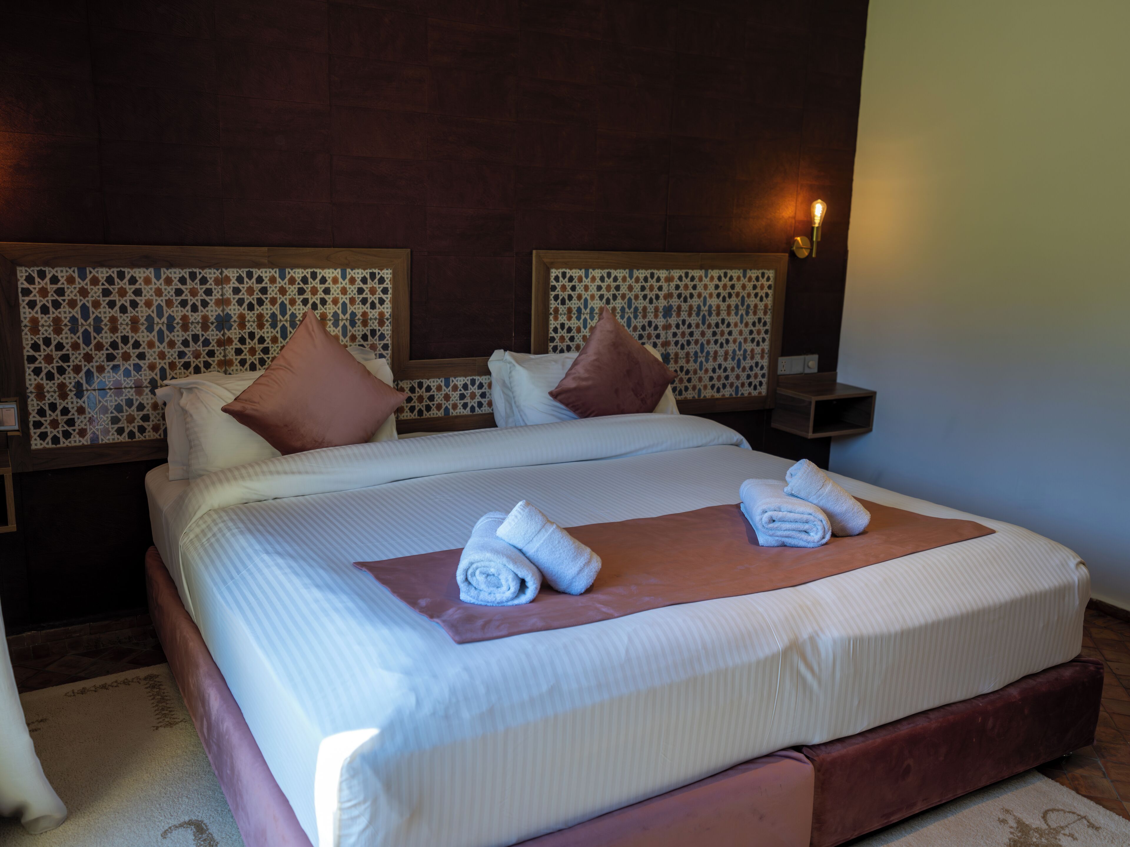 Una habitación de hotel con una cama grande, dos mesitas de noche y un cabecero estampado.
