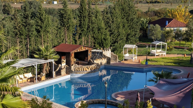 A large outdoor swimming pool with a stone structure, lounge chairs, and a gazebo. - Dar Ba Sidi & Spa (Derdara)