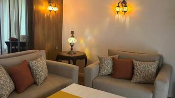 Una sala de estar con dos sofás, una mesa de centro, una lámpara y apliques de pared.