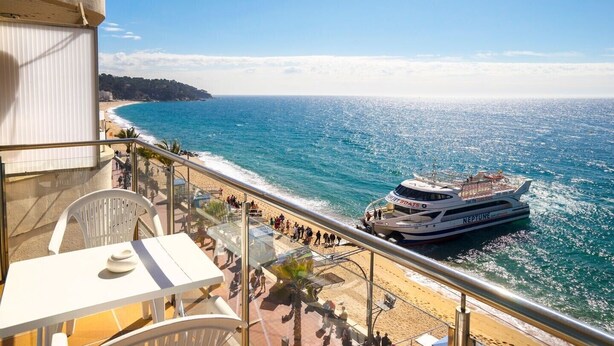 Un balcón con vista a una playa y un crucero Neptune.