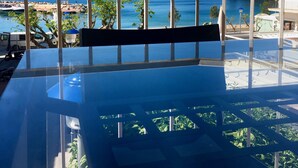 A balcony with a clear view of the sea and a hotel building in the background.