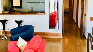 A modern living room with a red sofa, a blue chair, and a wooden floor.