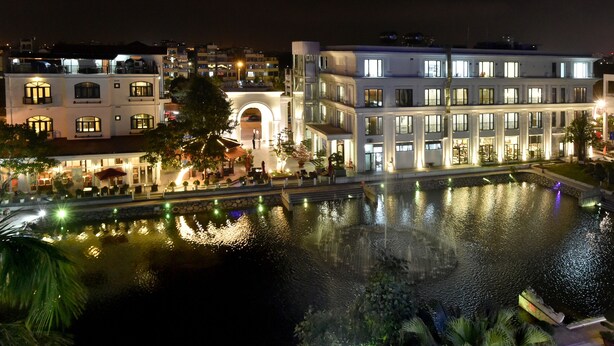 Um hotel moderno com piscina, janelas iluminadas e entrada bem iluminada.