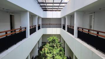 Ein mehrgeschossiges Interieur mit einem zentralen Atrium, weißen Wänden und einer Glasdecke.