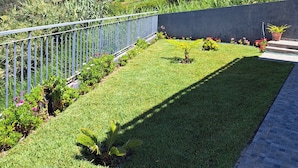 A well-maintained garden with a metal fence, a paved pathway, and a view of a mountainous landscape. - Peaceful Escape Between Ocean and Mountains - Conceição House (Lombo Do Doutor)