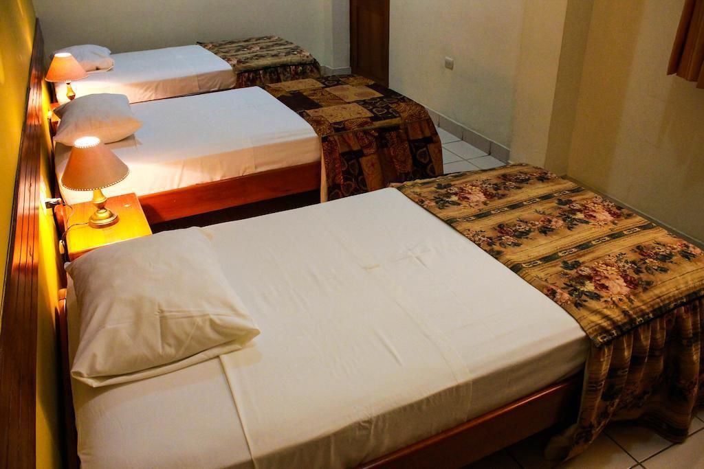 Una habitación con dos camas individuales, cada una con una mesita de noche y lámpara. Las camas tienen cubrecamas con estampado floral.