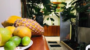 A table with a plate of fruits including a pineapple, oranges, and limes. - Sol de Selva Hostal (Tarapoto)
