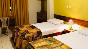 A hotel room with two beds, a desk, a chair, an air conditioner, and a framed picture on the wall. - Sol de Selva Hostal (Tarapoto)