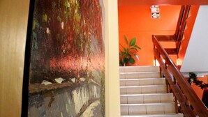 A staircase with wooden handrails and beige steps, leading to an orange wall with a potted plant. - Sol de Selva Hostal (Tarapoto)