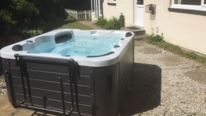 Un jacuzzi se trouve devant une maison avec une porte et des fenêtres blanches.