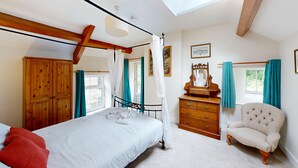 A bedroom with a canopy bed, wooden wardrobe, a vanity with a mirror, and a chair. - 19th century stable with four poster, river views and free WiFi (SWANSEA)
