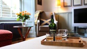 Un salon avec un canapé, une petite table sur laquelle se trouvent une bouteille et des verres, et une lampe.