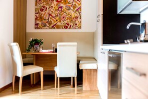 Cozinha moderna com área de refeições, armários de madeira e arte abstrata colorida na parede.