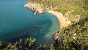 Un paisaje costero con playa, costa rocosa y colinas boscosas.