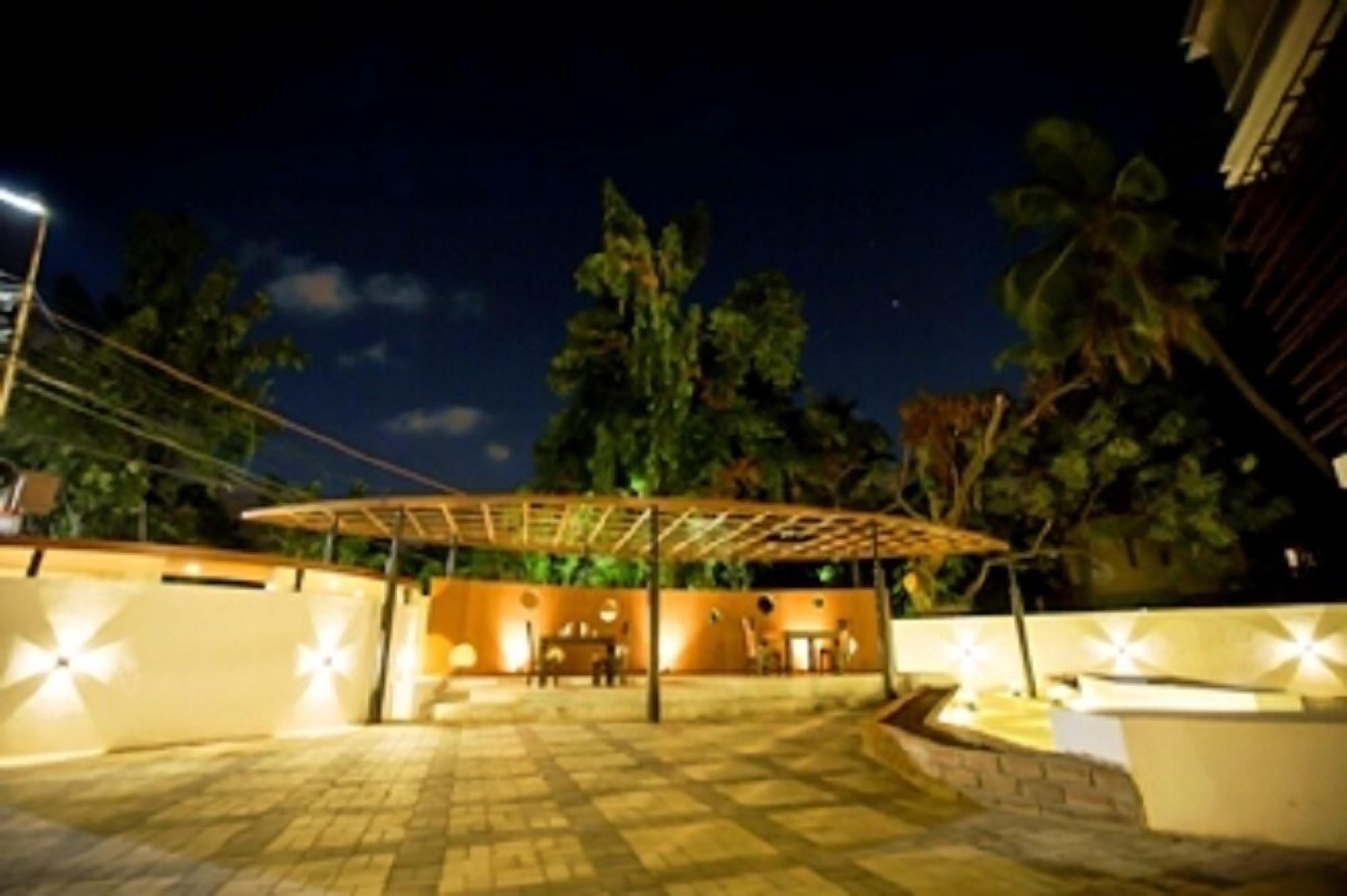 Un espace extérieur aménagé en terrasse, avec une pergola, des sièges et un éclairage d’ambiance.