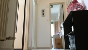 A hallway with a white door, a black shelf with a glass, and a wicker basket. - The moon and the bonfire IT009024C2SF9H64V7 (Ceriale)