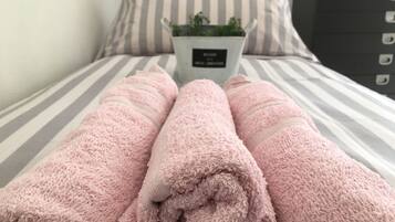 Una cama con ropa de cama a rayas y una planta en maceta sobre la mesita de noche.