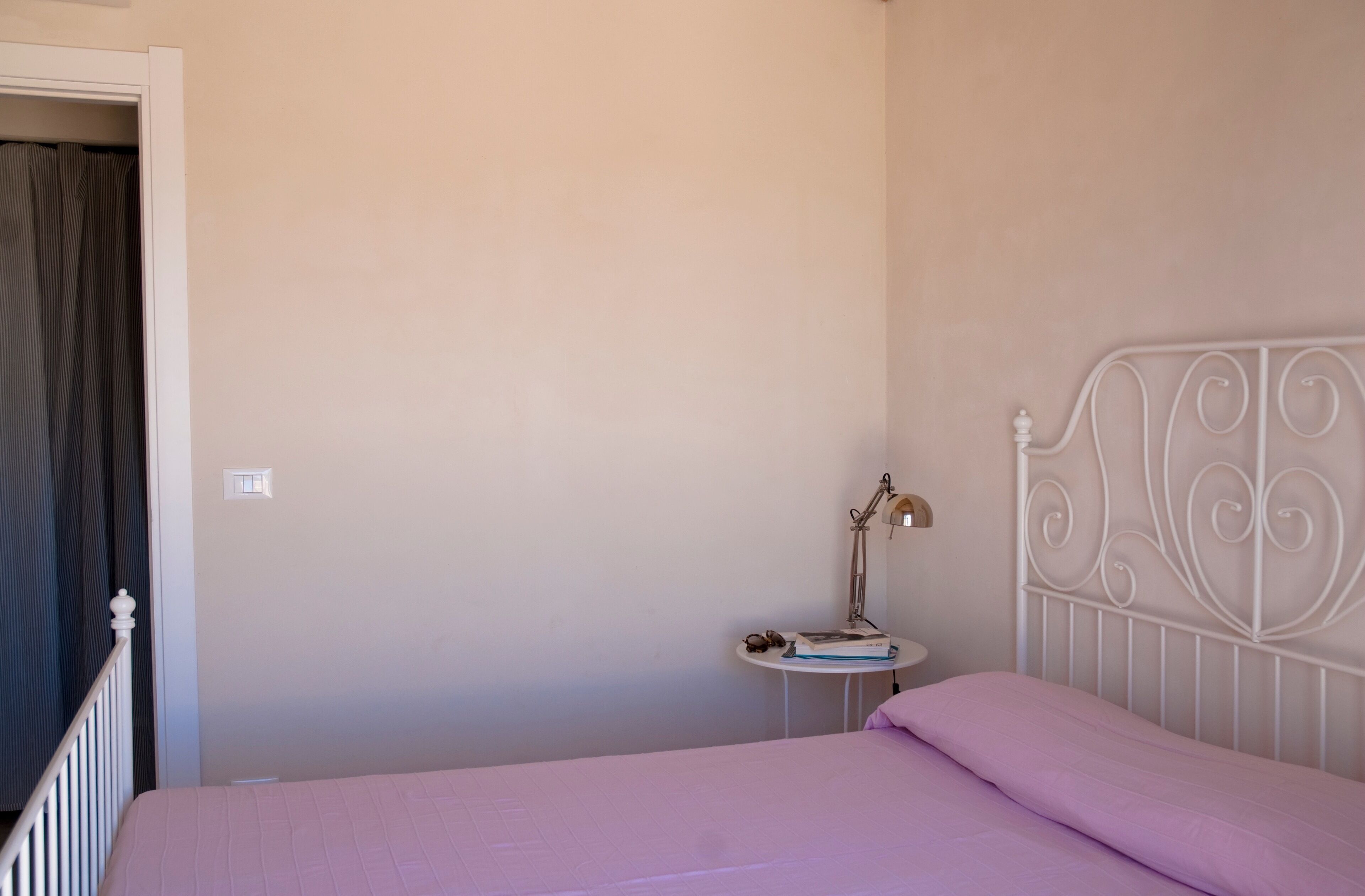 Une chambre à coucher avec un lit, une table de chevet, une lampe et un rideau.