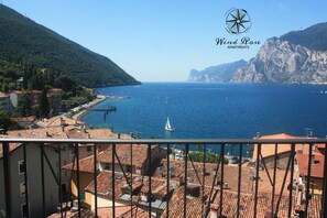 Vista costera con cielo despejado, un velero en el agua y montañas al fondo.