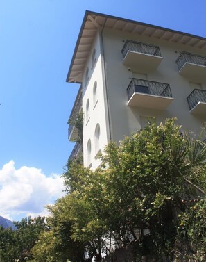 Un immeuble à plusieurs étages doté de balcons, entouré d’une végétation luxuriante.