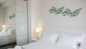 Ein Hotelzimmer mit Bett, Nachttisch mit Lampe, großem Spiegel und Wandbild mit Fischen.
