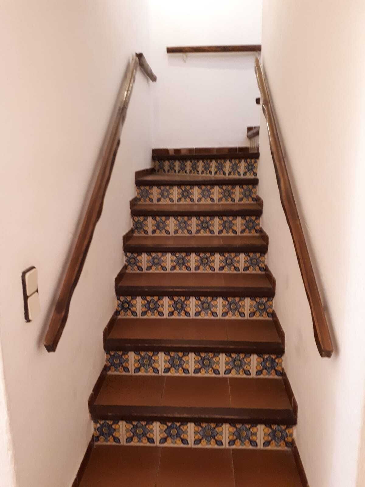 A staircase with patterned tiles and wooden handrails.